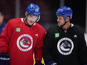 Former Vancouver Canucks defenceman Kevin Bieksa (right) talks with captain Bo Horvat as he skates at the start of practice in Vancouver, on Thursday, Nov. 3, 2022.