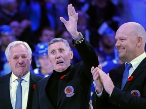 Borje Salming waves to the crowd as former Toronto Maple Leafs Darryl Sittler, left, and Mats Sundin stand by his side at centre ice in Toronto on Friday night.