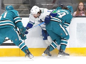 Vancouver Canucks right-winger Conor Garland (8) is checked into the boards by San Jose Sharks left wing Alexander Barabanov (94) during the first period at SAP Center at San Jose.