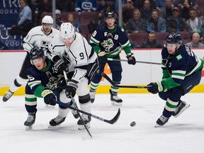 Vancouver Canucks forward Nils Hoglander (21) checks out Los Angeles Kings forward Adrian Kempe (9) as forward Sheldon Dries (15) checks out during the first period at Rogers Arena on November 18, 2022. I'm watching you do