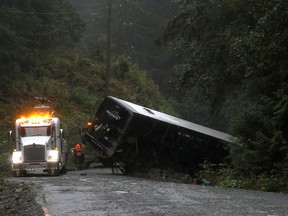 A tow-truck crew removes a bus from an embankment next to a logging road near Bamfield in 2019.