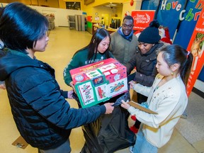 Volunteers from Guildford Park secondary school present people with gifts from the Surrey Christmas Bureau.