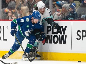 Canucks centre Elias Pettersson squeezes out Brandon Tanev of the Seattle Kraken along the boards during the first period of their Dec. 22, 2022 NHL game at Rogers Arena.