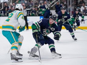 San Jose Sharks left wing Jonah Gadjovich (42) and Vancouver Canucks defenceman Quinn Hughes (43) compete for possession of the puck during the first period.