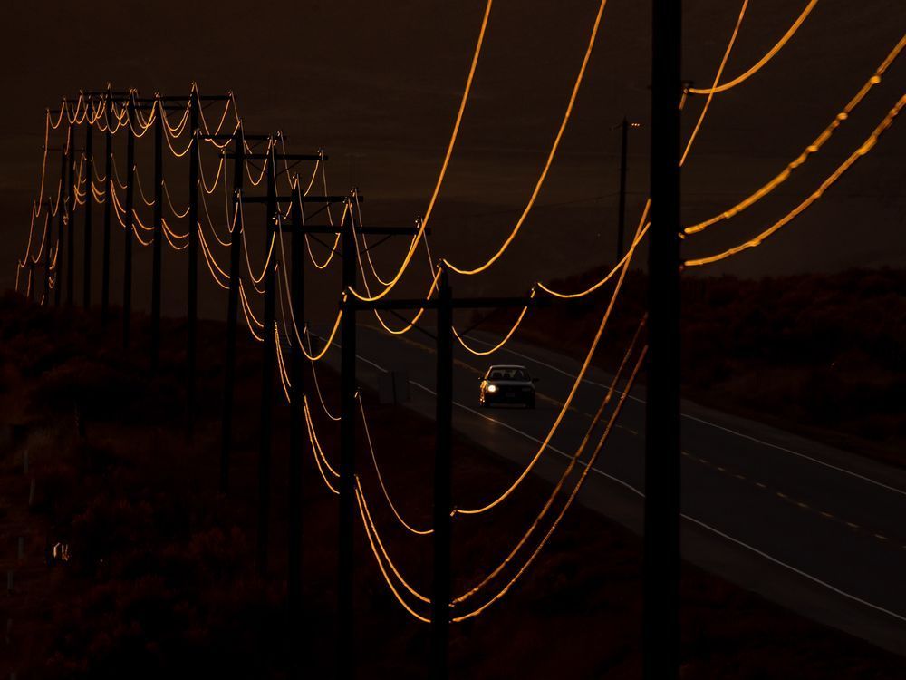 The setting sun reflects off of power lines as a motorist travels on the Trans-Canada Highway in Walhachin, B.C., west of Kamloops, on Tuesday, March 29, 2022. The B.C. government is temporarily suspending requests for electricity connections from cryptocurrency mining operations, saying the decision is aimed at preserving the power supply while supporting climate action and economic goals.