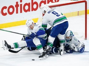 Vancouver Canucks goaltender Collin Delia (60) keeps his eye on the rebound as Curtis Lazar (20) and J.T. Miller (9) defend against Winnipeg Jets' Josh Morrissey (44) during the first period on Thursday in Winnipeg.