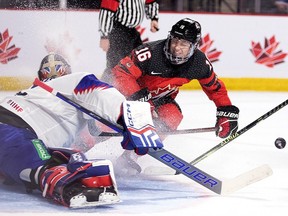 Canada's Connor Bedard, right, drives to the net as Slovakia goaltender Patrik Andrisik makes a save during a world junior hockey championship pre-tournament game in Moncton on Wednesday