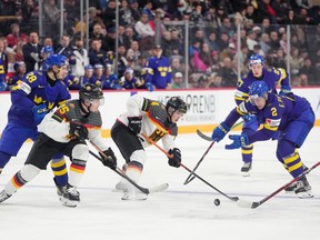 Germany’s Philip Sinn, centre, and Sweden’s Elias Pettersson battle for the puck during the second period.