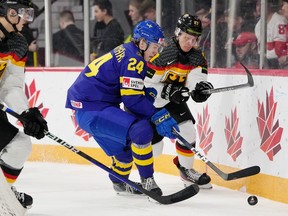Sweden’s Jonathan Lekkerimaki, left, and Germany’s Julian Waser battle for the puck during first period IIHF World Junior Hockey Championship action in Halifax on Tuesday, Dec. 27, 2022.