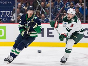Vancouver Canucks forward Elias Pettersson (40) and Minnesota Wild defenseman Jake Middleton (5) battle for a rebound in the first period at Rogers Arena Dec. 10, 2022.