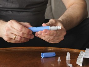 A man prepares an Ozempic dispenser for injection.