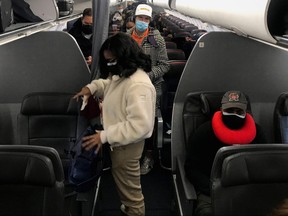 Travellers wearing masks prepare to get off an American Airlines flight at Ronald Reagan Washington National Airport in Washington, D.C., Dec. 18, 2021.