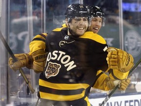 Bruins forward Jake DeBrusk (74) celebrates with teammates after scoring a goal against the Penguins during the third period in the 2023 Discover NHL Winter Classic at Fenway Park in Boston, Monday, Jan. 2, 2023.