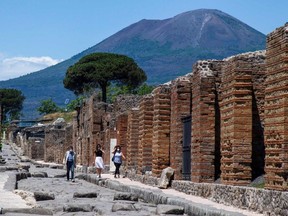 On May 26, 2020, visitors walk across the archeological site of Pompeii at the bottom of the Mount Vesuvius volcano.
