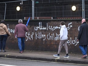 Pedestrians walk past graffiti daubed on a wall outside the Iranian Embassy in London on January 14, 2023. - Britain on Saturday said the "barbaric" hanging in Iran of former top defence official and dual British national Alireza Akbari, who was accused of spying for UK intelligence, would not go unchallenged. "This barbaric act deserves condemnation in the strongest possible terms. This will not stand unchallenged," Foreign Secretary James Cleverly said. (Photo by JUSTIN TALLIS / AFP)