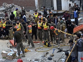 Security officials and rescue workers gather at the site of suicide bombing, in Peshawar, Pakistan, Monday, Jan. 30, 2023.