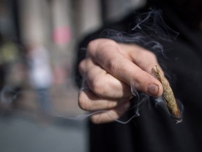 A man holds a joint while smoking marijuana, in Vancouver in 2018. British Columbia has released the results of its public engagement to help inform the government's decision on allowing spaces for consuming cannabis.