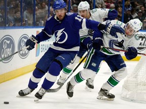 Tampa Bay Lightning left wing Boris Katchouk (13) pushes away Vancouver Canucks defenceman Quinn Hughes (43) as he moves the puck during a game on Jan. 13, 2022, in Tampa, Fla.
