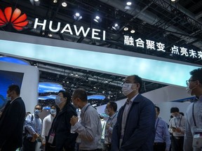 Visitors walk past a booth for Chinese technology firm Huawei at the PT Expo in Beijing on Sept. 28, 2021.