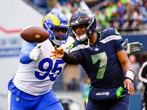 Seattle Seahawks quarterback Geno Smith (7) passes under pressure from Los Angeles Rams defensive tackle Bobby Brown III (95) during the second quarter at Lumen Field.