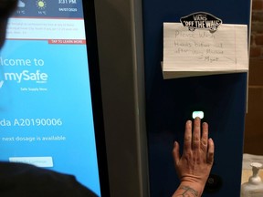 A woman demonstrates how the MySafe narcotic dispensing machine uses a palm-print ID.