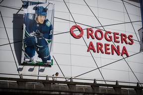 A woman walks past a large photo of Vancouver Canucks captain Bo Horvat outside Rogers Arena, home to the NHL team, in Vancouver, on Thursday, March 12, 2020. The National Hockey league has suspended the season due to concerns about the coronavirus.