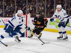 Vancouver Canucks forward Conor Garland (8) and Tampa Bay Lightning defenceman Ian Cole (28) watch as forward Steven Stamkos (91) handles the puck in the first period at Rogers Arena in January 2023.