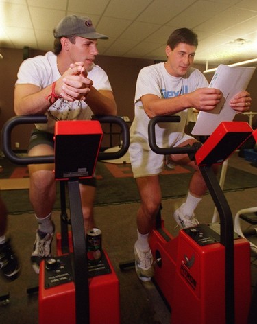 Gino Odjick chats with recent arrival and returnee Jim Sandlak while riding the bike on Oct. 10, 1995.