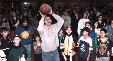 Gino Odjick shoots a basket while surrounded by kids at the Squamish Nation Recreation Center in North Vancouver.