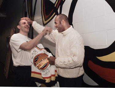 Gino Odjick gets teased by Donald Brashear,  after he signed a souvenir jersey for him.