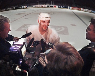 Basking in the media spotlight, the hero of the previous night's playoff win, Gino Odjick, is surrounded by the media at the end of practice.