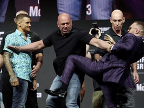 Dana White (centre) intervenes as Conor McGregor (right) throws a kick at Dustin Poirier during a UFC press conference in 2021.