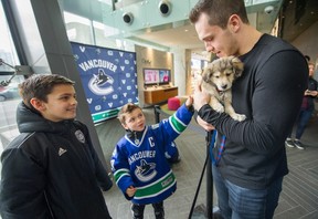 Vancouver Canucks Bo Horvat with Mikhail, age 10 (far left) and Laith, age 7 (centre), cuddle puppies during Cupcakes and cuddles fundraiser for the SPCA at Telus Garden in Vancouver, BC,  February 13, 2018. (Arlen Redekop / PNG staff photo)
