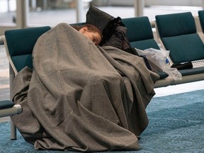A woman gets some sleep on a couple of Vancouver International Airport terminal seats as delays and cancelled flights abound due to snowy weather on Dec. 23, 2022.