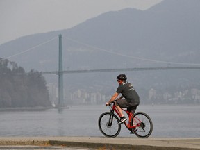 A cyclist bikes along the seawall as smoke shrouds the skyline as wildfires contribute to poor air quality in Vancouver, British Columbia, Canada, September 12, 2022.
