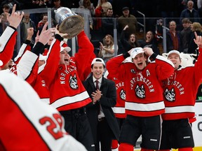 Aidan McDonough #25 of the Northeastern Huskies raises the Beanpot trophy after a victory against the Harvard Crimson in the championship game of the annual tournament at TD Garden in Boston.