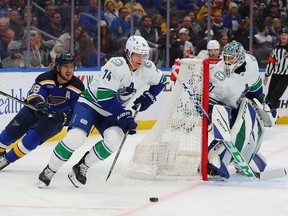 Ethan Bear of the Vancouver Canucks controls the puck against Robert Thomas of the St. Louis Blues as Arturs Silovs of the Vancouver Canucks looks on in the first period at Enterprise Center on February 23, 2023 in St Louis, Missouri.