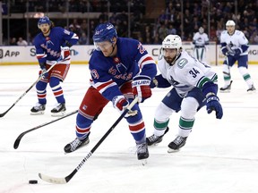 Adam Fox #23 of the New York Rangers controls the puck as Phillip Di Giuseppe #34 of the Vancouver Canucks chases during the 1st period of the game at Madison Square Garden on February 08, 2023 in New York City.