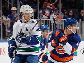 Elias Pettersson of the Vancouver Canucks exchanges high sticks with former teammate Bo Horvat (right) of the New York Islanders during their Feb. 9, 2023 NHL game at UBS Arena in Elmont, N.Y.