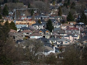 A condo building is seen under construction surrounded by houses in Vancouver. The B.C. speculation and vacancy tax applies to homeowners in Metro Vancouver and other communities with housing shortages.