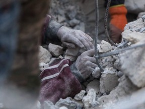 A rescue worker digs to reach a boy under the rubble of a collapsed building in the rebel-held town of Jindayris on Feb. 8, 2023, two days after a deadly earthquake that hit Turkey and Syria.
