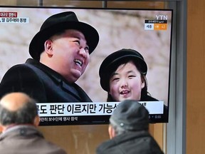 People watch a television screen showing a news broadcast with an image of North Korean leader Kim Jong Un and his daughter presumed to be named Ju Ae attending a military parade held in Pyongyang to mark the 75th founding anniversary of its armed forces, at a railway station in Seoul on Feb. 9, 2023.