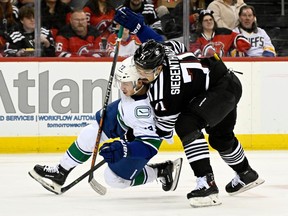 New Jersey Devils defenceman Jonas Siegenthaler, right, checks Vancouver Canucks left wing Anthony Beauvillier (72) during the first period.