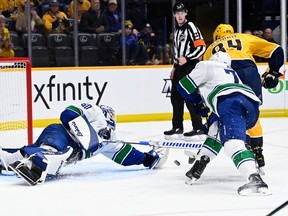 Vancouver Canucks goaltender Collin Delia (60) dives to block a shot by Nashville Predators left wing Tanner Jeannot (84) during the second period on Tuesday, Feb. 21, 2023, in Nashville, Tenn.