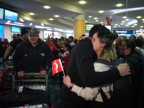 A woman embraces a member of the Burnaby Urban Search and Rescue Team as they are greeted by members of the Turkish Canadian community upon arrival from Turkey at Vancouver International Airport, in Richmond, B.C., on Tuesday, February 14, 2023.