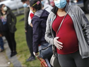 The British Columbia government has spent $1.7 million to expand University of British Columbia's midwifery program from 28 seats to 48 seats. A pregnant woman holds her belly as she waits in line for groceries, at St. Mary's Church in Waltham, Mass., Thursday, May 7, 2020.