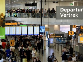 Travellers wait in long lines to check in and board flights at Amsterdam's Schiphol Airport, Netherlands, on June 21, 2022.