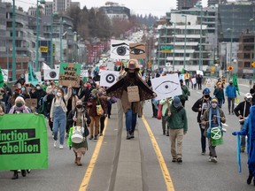 People taking part in an Extinction Rebellion protest against old-growth logging march onto the empty Cambie Bridge, in Vancouver, B.C., Saturday, March 27, 2021. A man who took part in four traffic-stopping protests in Metro Vancouver in an effort to save old-growth forests has been given a conditional sentence and six months probation.