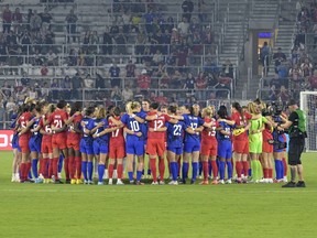Members of the U.S. and Canadian teams meet on the field in a show of unity before a SheBelieves Cup soccer match on Thursday in Orlando, Fla.