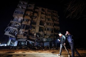 People walk past a building affected by an earthquake in Antakya, Hatay Province, Turkey Feb. 7, 2023.
